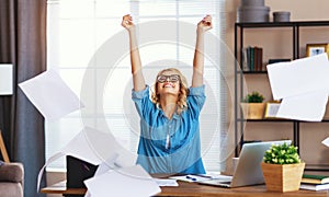 Young happy business woman working on computer and  throws up   papers in   office