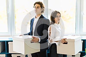 Young happy businessman and a business woman with boxes for moving into a new office