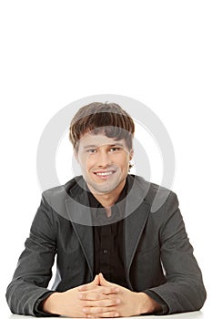 Young happy businessman sitting behind the desk