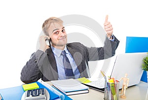 Young happy businessman smiling confident talking on mobile phone at office computer desk