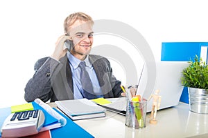 Young happy businessman smiling confident talking on mobile phone at office computer desk