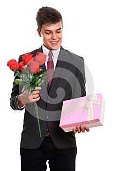 Young happy businessman smiling while holding red roses and look