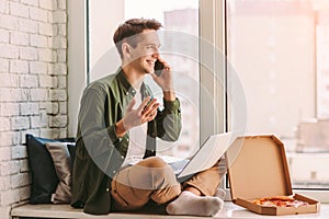 Young happy businessman talking mobile phone while working at home office