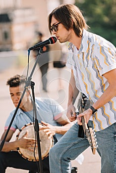 Young happy buskers drummer and guitarist playing music