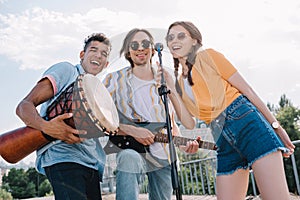 Young happy buskers singing by microphone