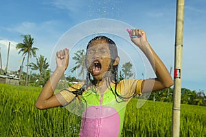 Young happy and carefree beautiful child 7 or 8 years old outdoors having shower at a beautiful rice terrace playful under the