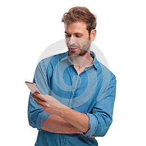 Young happy casual man reads sms message on his phone