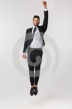 Young happy caucasian businessman jumping and flying in the air , isolated on white background