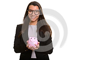 Young happy Caucasian businesswoman smiling and holding piggy ba
