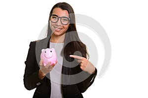 Young happy Caucasian businesswoman smiling and holding piggy ba