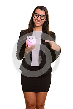 Young happy Caucasian businesswoman smiling and holding piggy ba