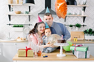 Young happy Caucasian family celebrating a first birthday party of their little baby boy