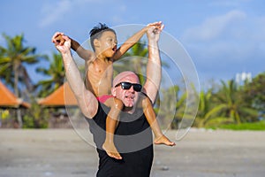 Young happy Caucasian man and his mixed Asian ethnicity young son at tropical beach Summer holidays the child sitting on father