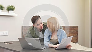 Young happy caucasian spouses sitting with laptop and documents