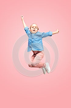 Young happy caucasian teen girl jumping in the air, isolated on pink studio background.