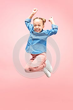Young happy caucasian teen girl jumping in the air, isolated on pink studio background.