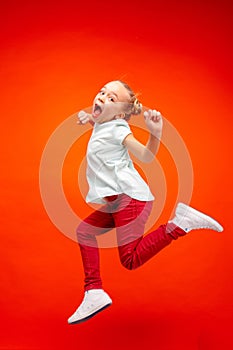 Young happy caucasian teen girl jumping in the air, isolated on red studio background.