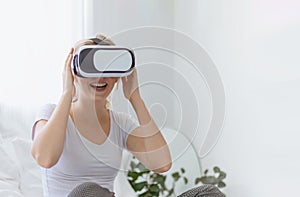 Young happy Caucasian woman enjoy using virtual reality goggles or headset device. futuristic and cyberspace experience at home.