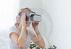 Young happy Caucasian woman enjoy using virtual reality goggles or headset device. futuristic and cyberspace experience at home.