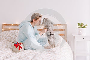 Young happy Caucasian woman playing with cute puppy dog pet at home. Pet owner celebrating Christmas holiday alone. Holiday