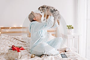 Young happy Caucasian woman playing kissing cute puppy dog pet at home. Pet owner celebrating Christmas holiday alone. Holiday