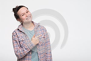 Young happy caucasian woman pointing upwards in studio and looking at camera