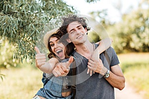 Young happy cheerful couple showing thumbs up and hugging