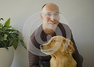 Young happy and cheerful man at home playing with his dog, a beautiful retriever, the guy smiling sweet cuddling the pet in