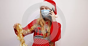 Young happy christmas woman, wearing a Santa Claus hat and a medical mask