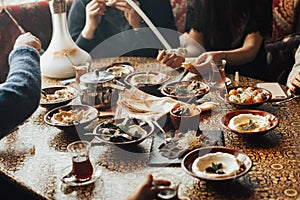 Young happy company of people is eating lebanon food and smokinh shisha. Lebanon cuisine.