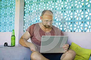 Young happy and confident backpacker man working with laptop computer outdoors relaxed as freelance entrepreneur and digital nomad