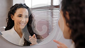 Young happy confident woman standing in bathroom looking in mirror rehearsing speech instructs preparing for interview