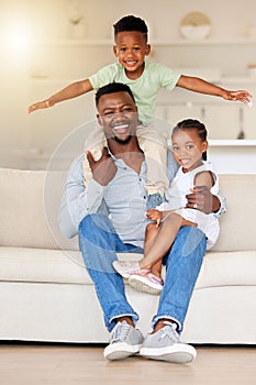 Young happy content african american father bonding and relaxing with his little son and daughter sitting on the couch