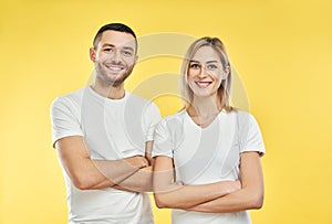 Young happy couple with arms crossed over yellow background
