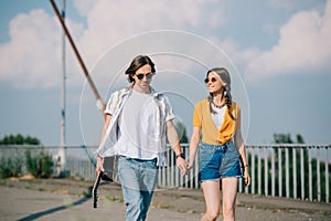 Young happy couple of buskers walking with guitar in hands