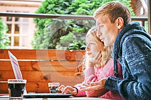 Young happy couple in a cafe at a laptop. man and girl have fun together and relax