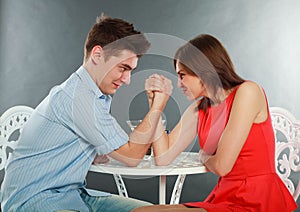 Young happy couple challenge fighting in arm-wrestling at table