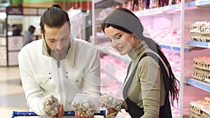 Young happy couple choose quail eggs in supermarket. Slow motion. Portrait.