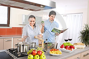 Young happy couple cook in kitchen with cookbook photo