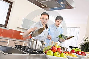 Young happy couple cook in kitchen with cookbook