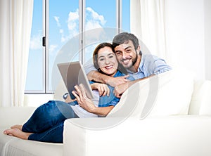 Young happy couple on couch at home enjoying using digital tablet