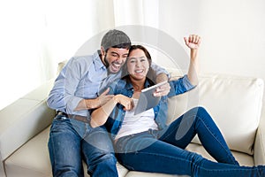 Young happy couple on couch at home enjoying using digital tablet computer