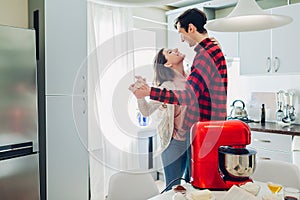 Young happy couple dancing on kitchen while cooking with food processor. Woman and man relaxing at home