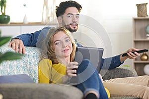 young happy couple with digital tablet on sofa at home