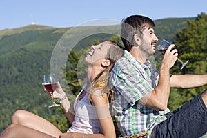 Young happy couple drinking wine on a hiking trip at the viewpoi
