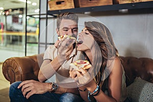 Young happy couple eating pizza in a restaurant
