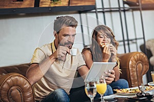 Young happy couple eating pizza in a restaurant