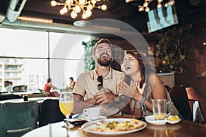 Young happy couple eating pizza in a restaurant and having fun