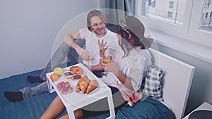 Young happy couple enjoying breakfast in bed