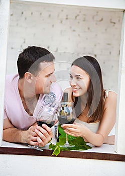 Young happy couple enjoying a glasses of red wine